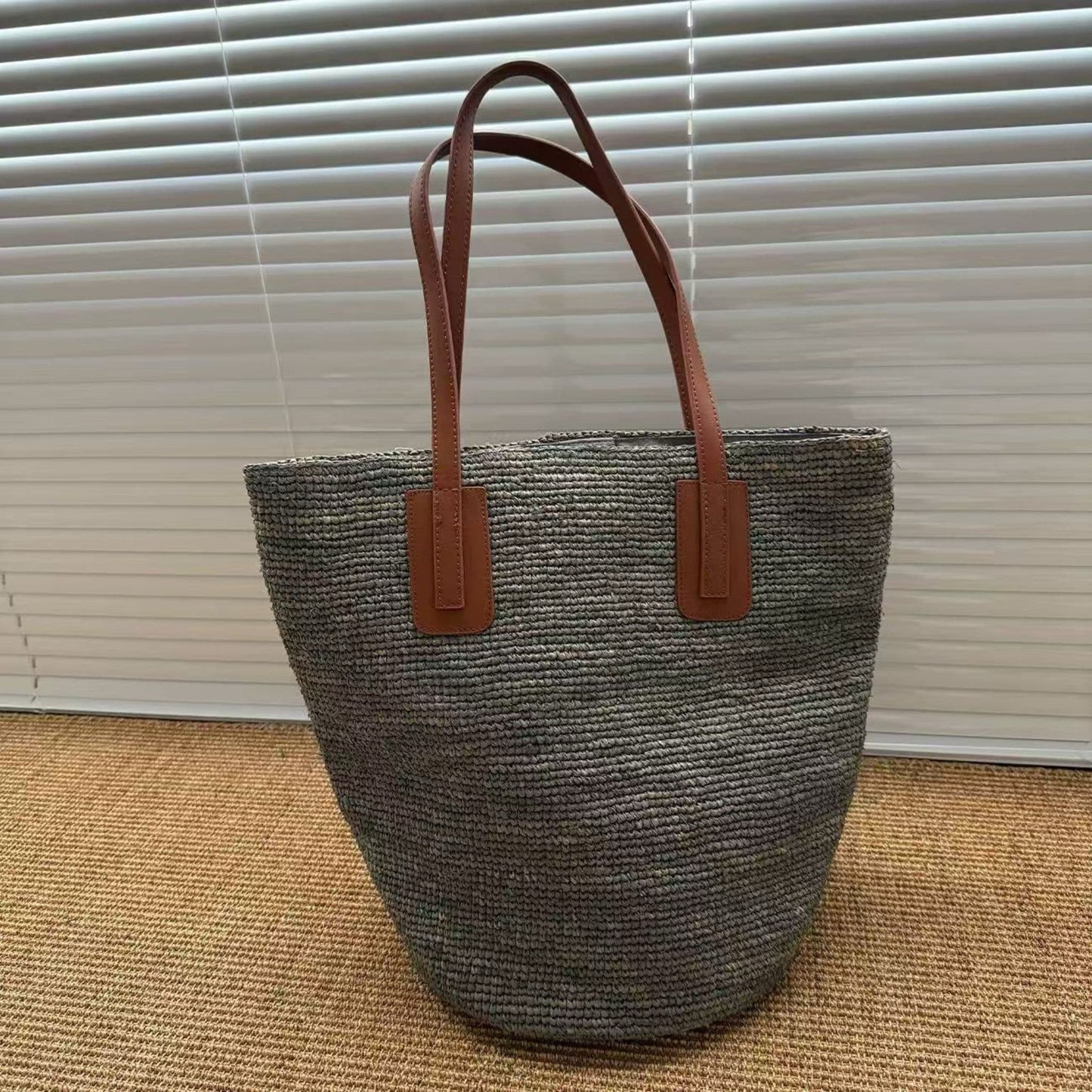 Gray handmade raffia tote bag with brown leather straps, front view