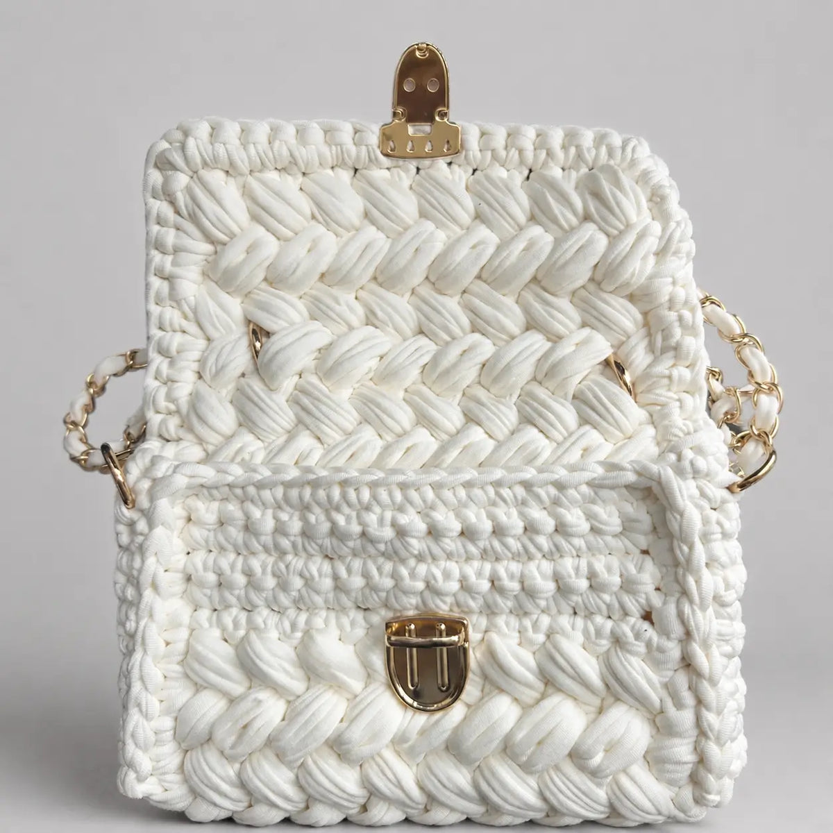 Open white crochet handbag showing the inside structure, chunky woven texture, and gold push-lock closure