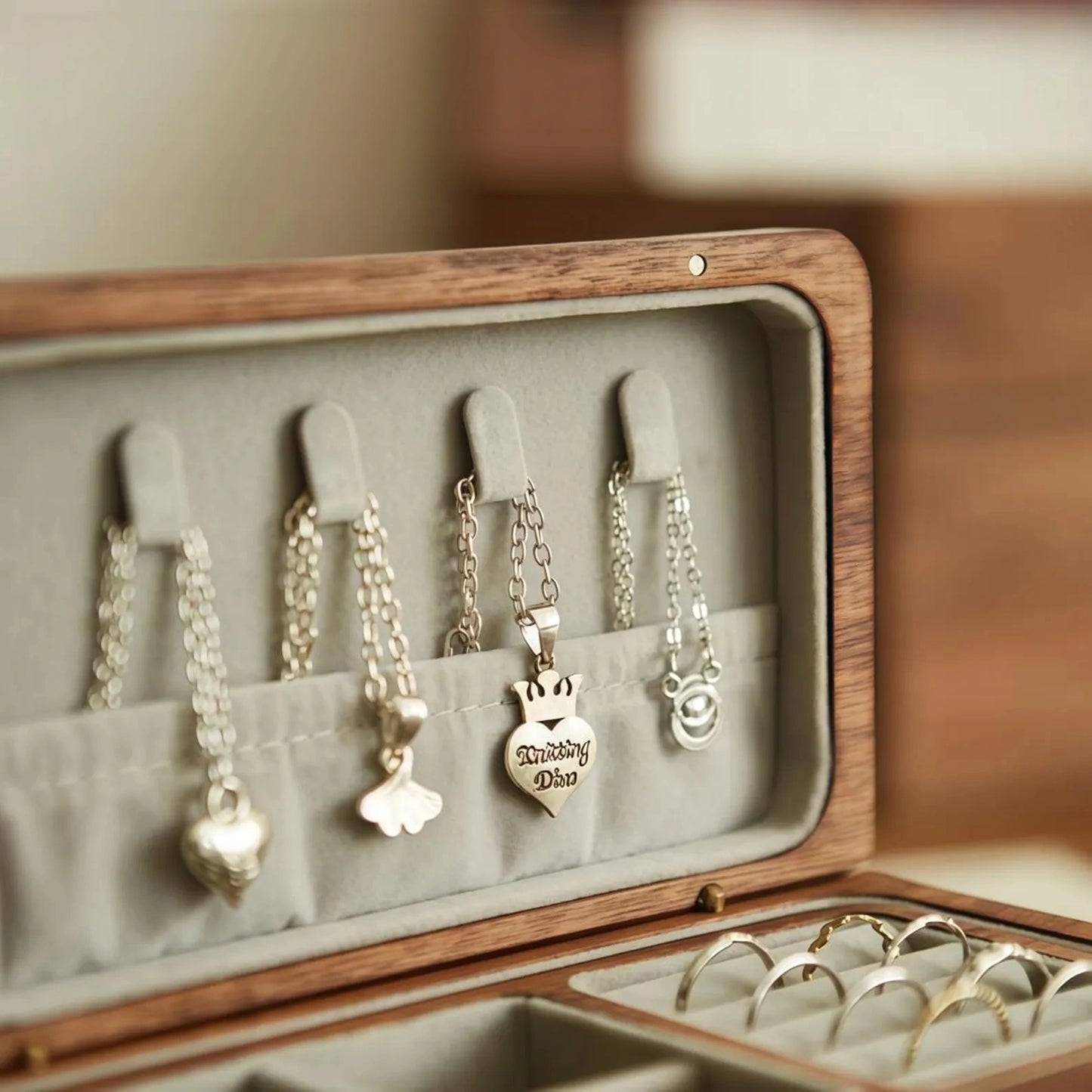 Close-up of velvet-lined necklace hooks and storage pocket inside the black walnut jewelry box lid