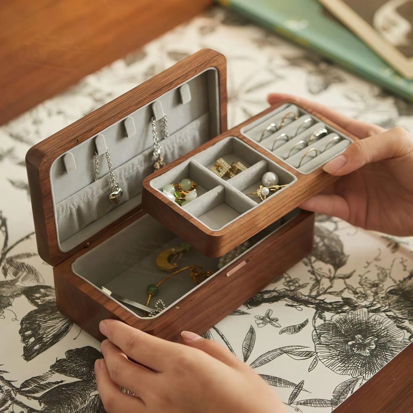 Removable upper tray lifted from a double-layer black walnut jewelry box, revealing additional storage below