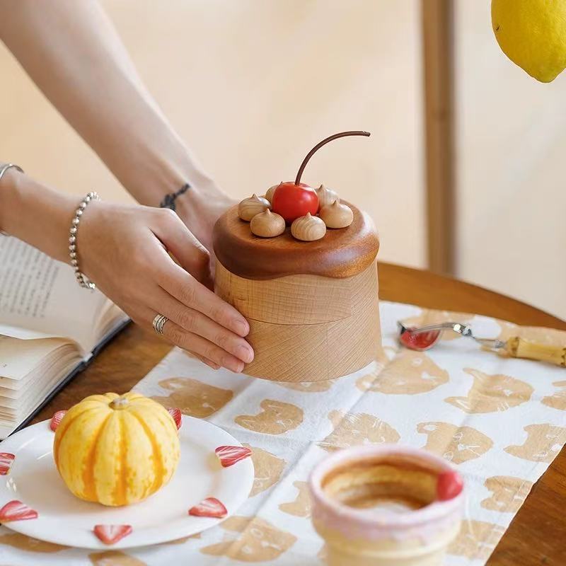 Cherry cake jewelry box held in both hands to show its compact size