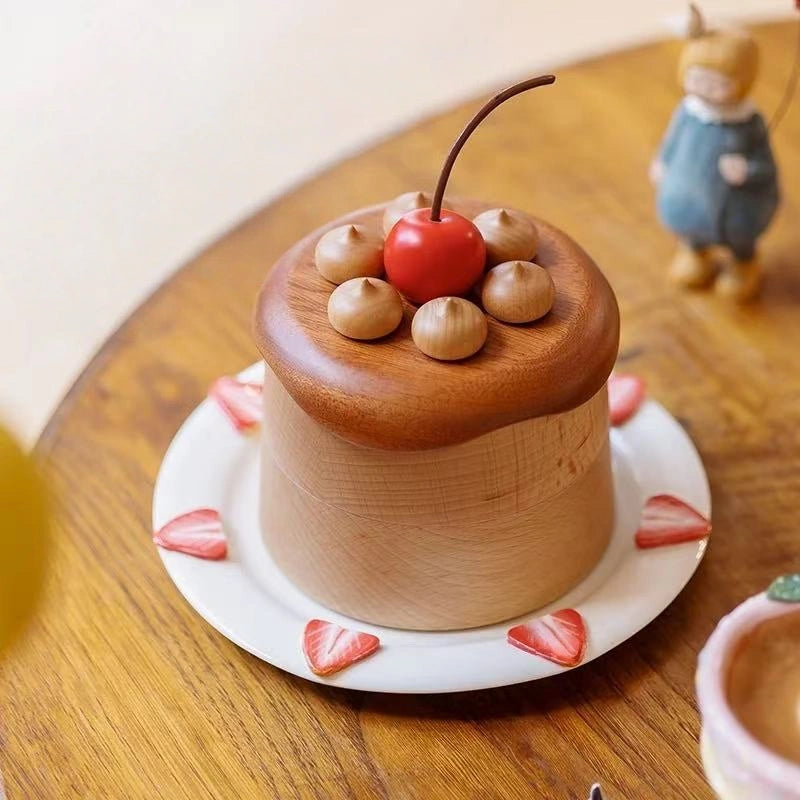 Wooden cherry cake jewelry box displayed on a plate on a warm tabletop