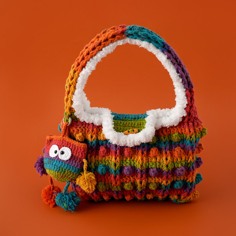 Colorful crochet handbag with white handle and a cute handmade character charm on an orange background.