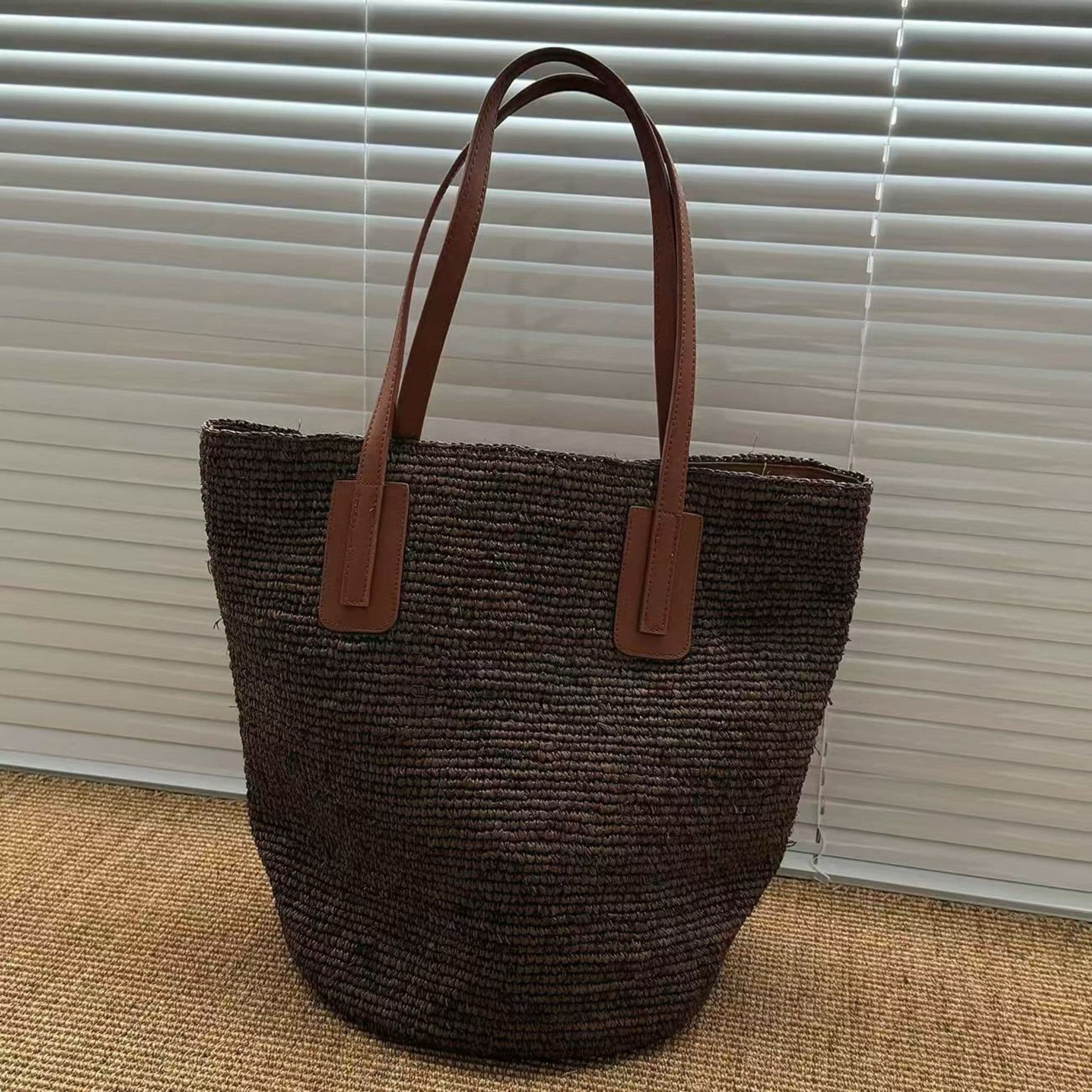 Dark brown handmade raffia tote bag with leather shoulder straps, front view