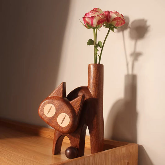 Dark wenge wooden cat bud vase displaying pink roses in warm afternoon light.