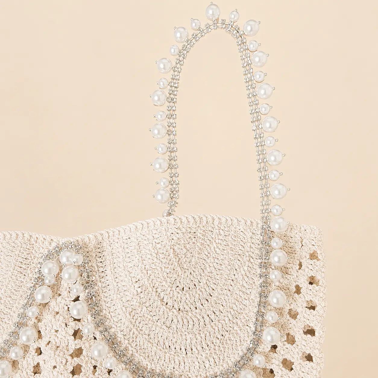 Close up of cream crochet top with pearl and rhinestone strap details
