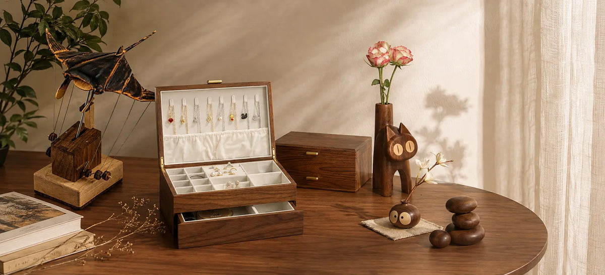 Open and closed walnut jewelry boxes with ivory lining on a warm wooden tabletop.