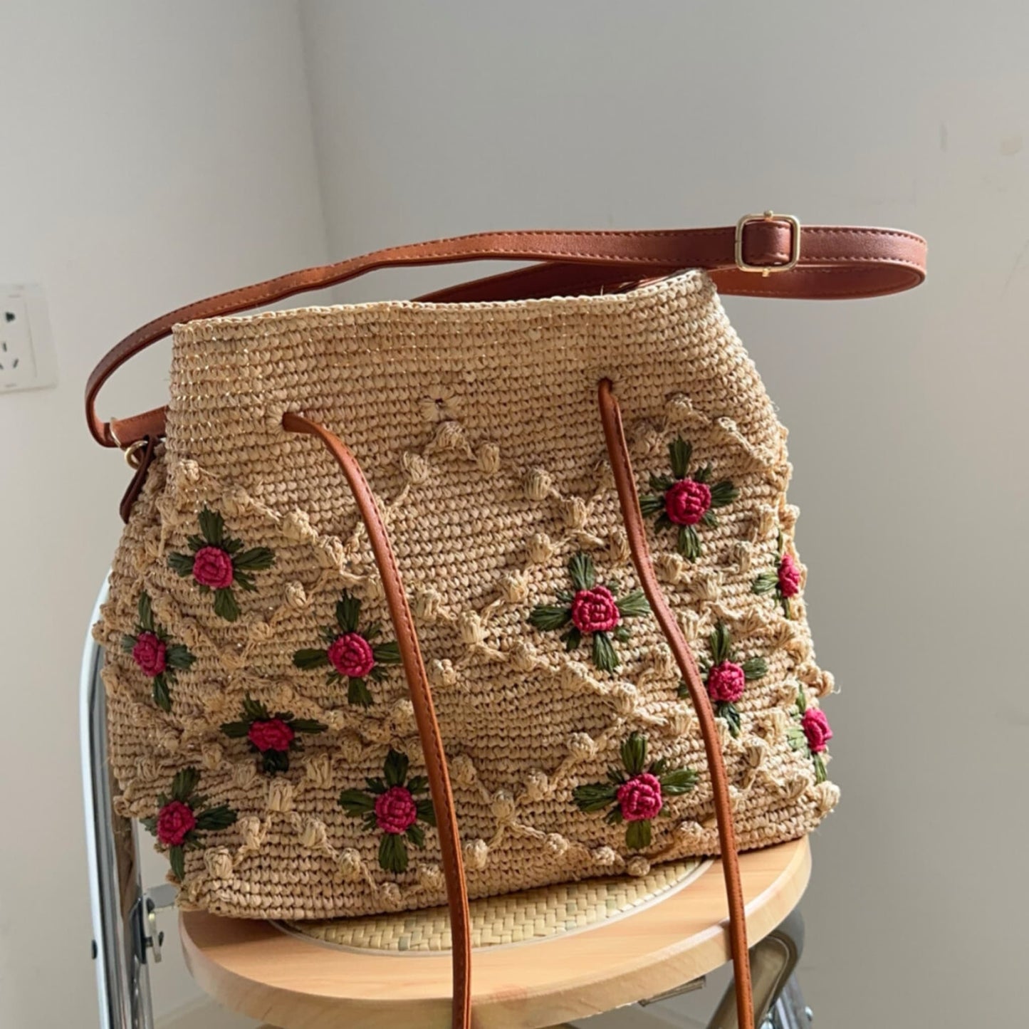 Handwoven natural raffia bucket bag with floral embroidery and leather
     straps
