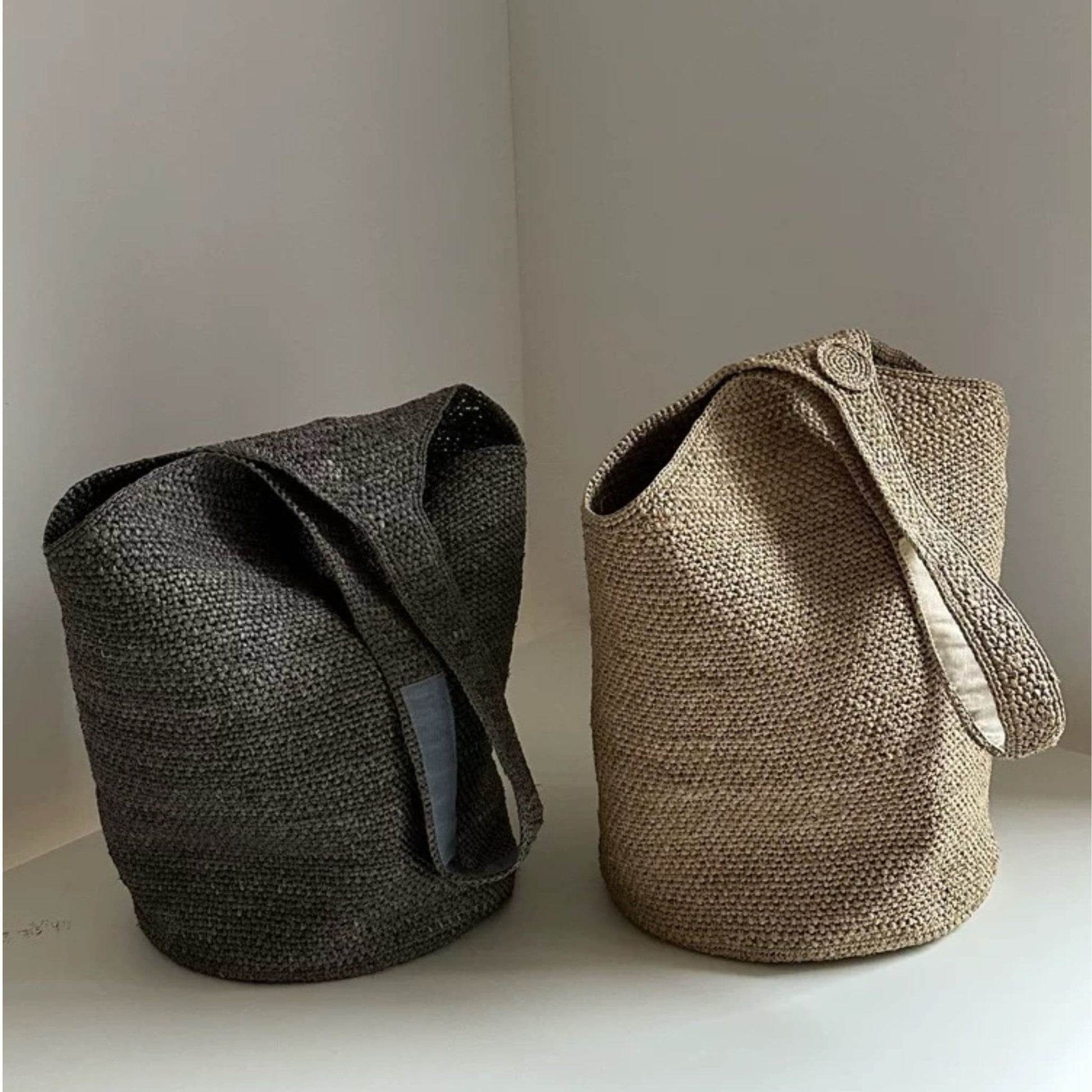 Gray and natural handwoven raffia bucket tote bags displayed together
