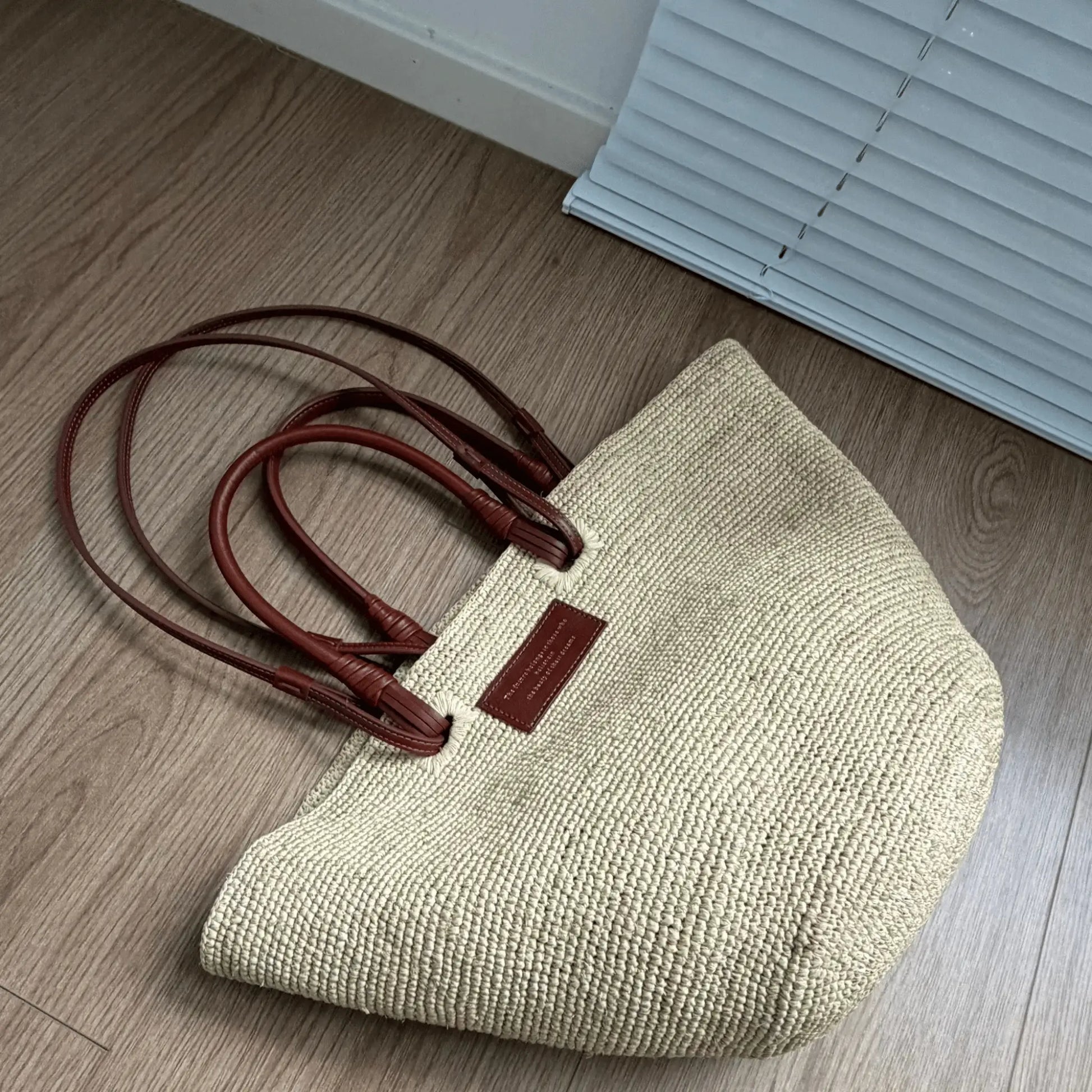 Top view of a handmade raffia basket bag with structured woven body and brown leather handles, ideal for beach, vacation, and everyday use