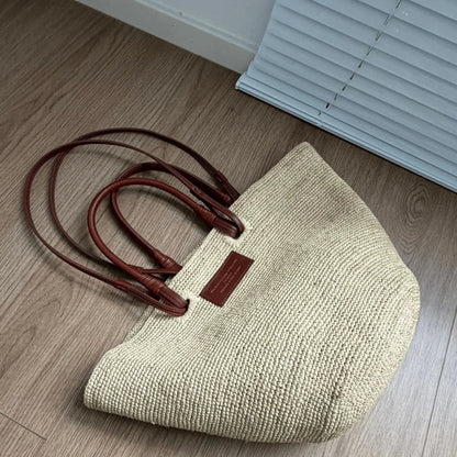 Top view of a handmade raffia basket bag with structured woven body and brown leather handles, ideal for beach, vacation, and everyday use