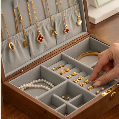Gray-lined jewelry box interior with necklace holders, ring rolls, and divided compartments