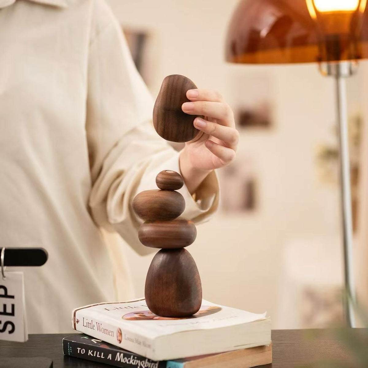 Person lifting a Black Walnut magnetic balance stone from a stacked wooden sculpture