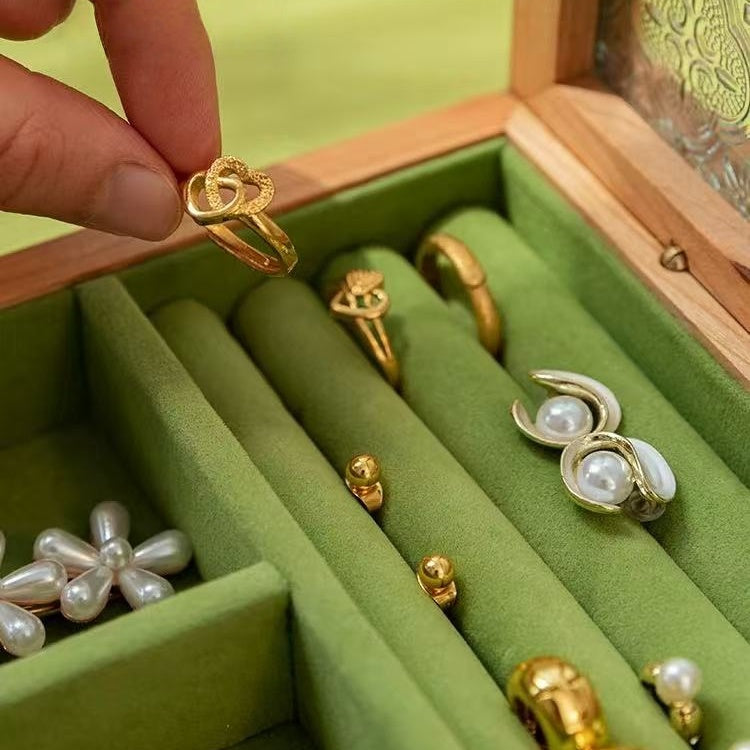 Close-up of rings set in green velvet ring rolls inside the cherry wood jewelry box.