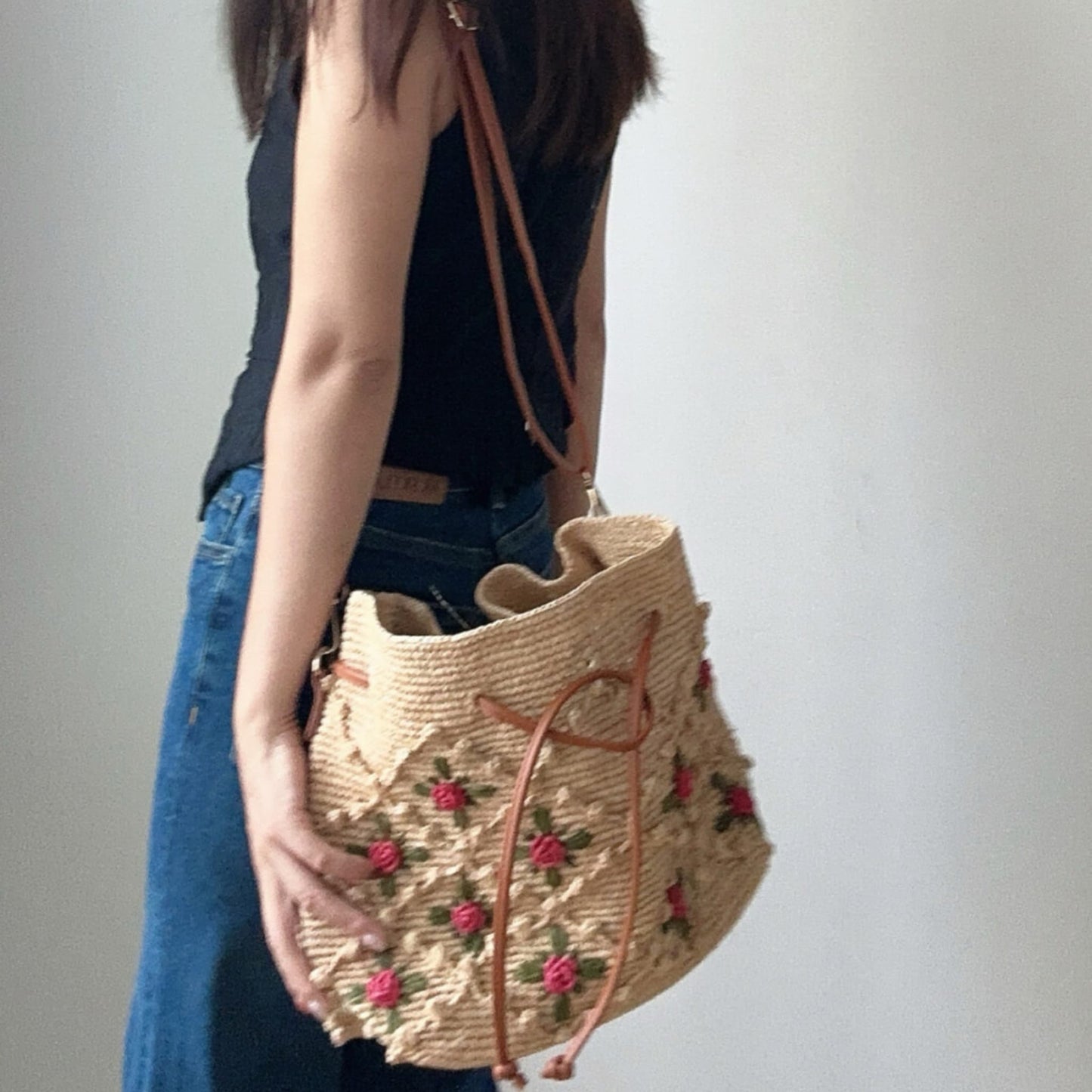 Woman carrying a handwoven floral raffia bucket shoulder bag