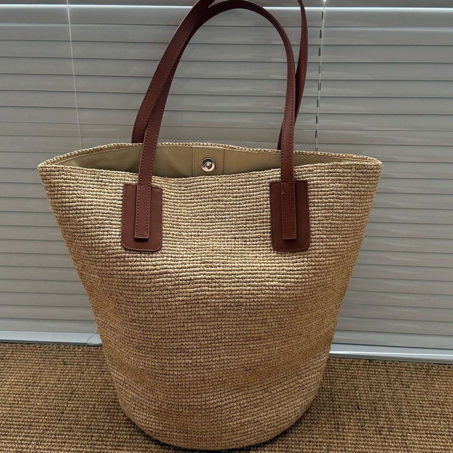 Large natural raffia tote bag with leather shoulder straps, front view