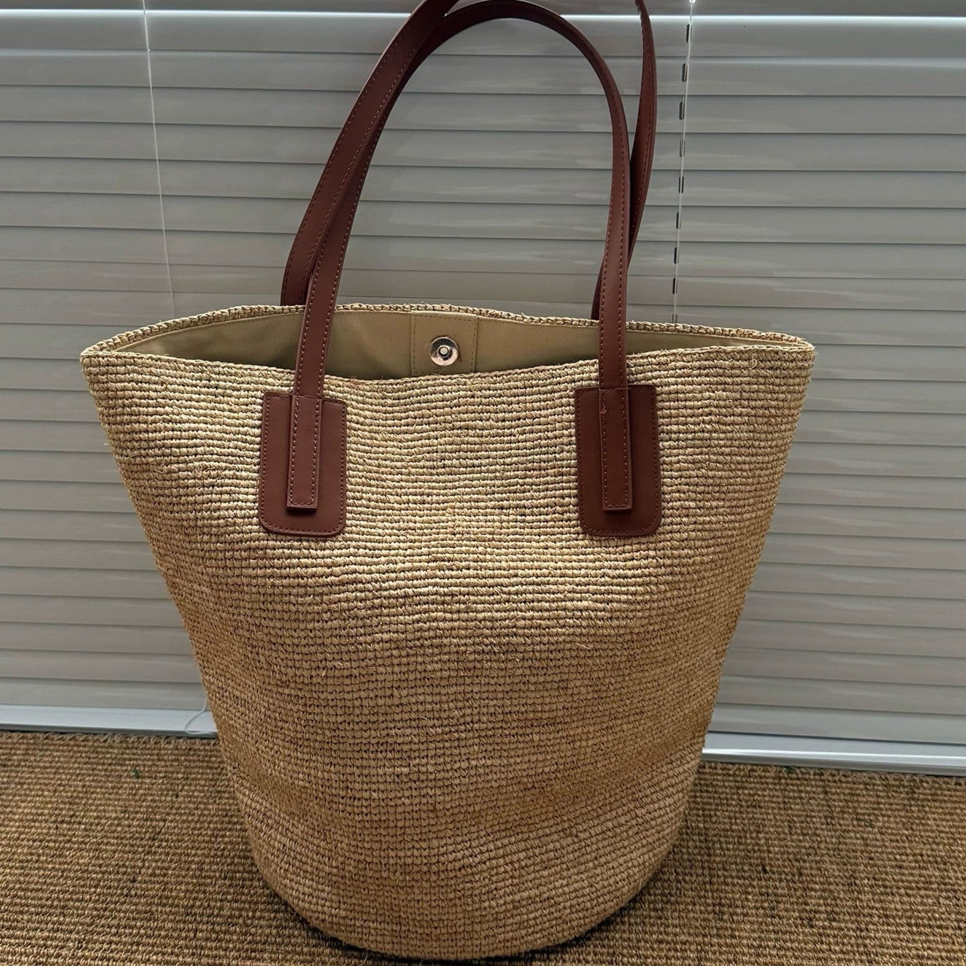 Large natural raffia tote bag with leather shoulder straps, front view