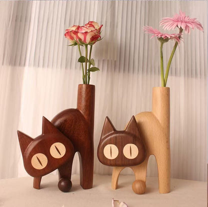 Two solid wood cat bud vases in dark wenge and light beech displaying fresh flowers.