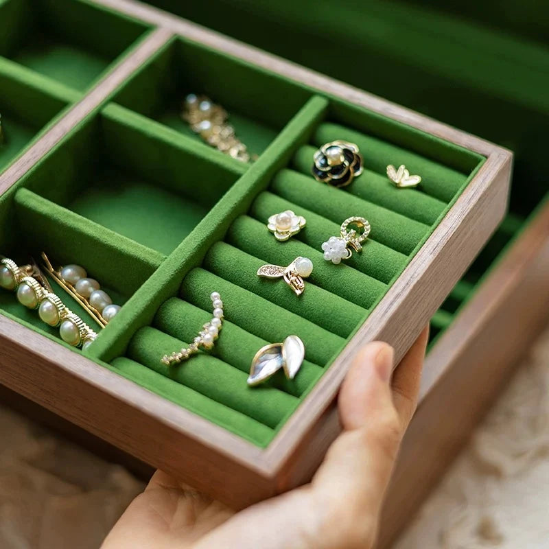 Close-up of green velvet ring rolls and earring compartments in the removable tray