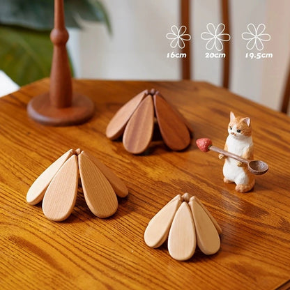 Three foldable wooden trivets shown closed in different sizes beside their storage stand.