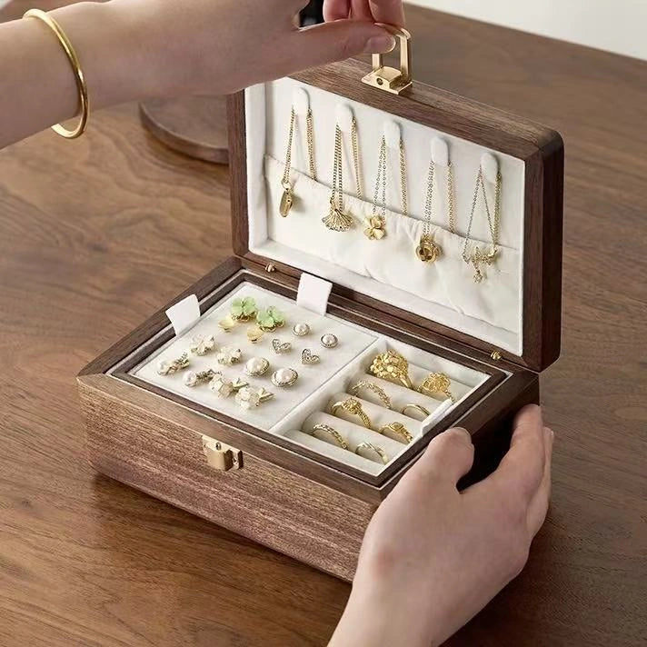 Open double-layer walnut jewelry box with an ivory-lined earring tray, ring rolls and necklace hooks.