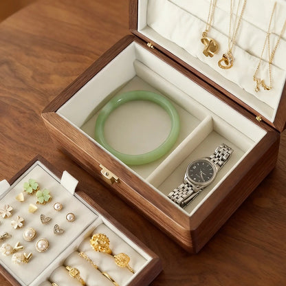 Close-up of the ivory-lined lower compartments in a double-layer walnut jewelry box holding a bangle and watch.