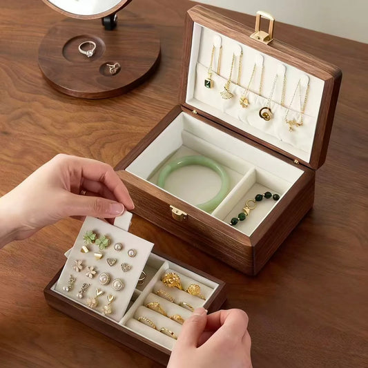 Hands lifting the ivory-lined tray from a double-layer walnut jewelry box to reveal the lower storage compartments.