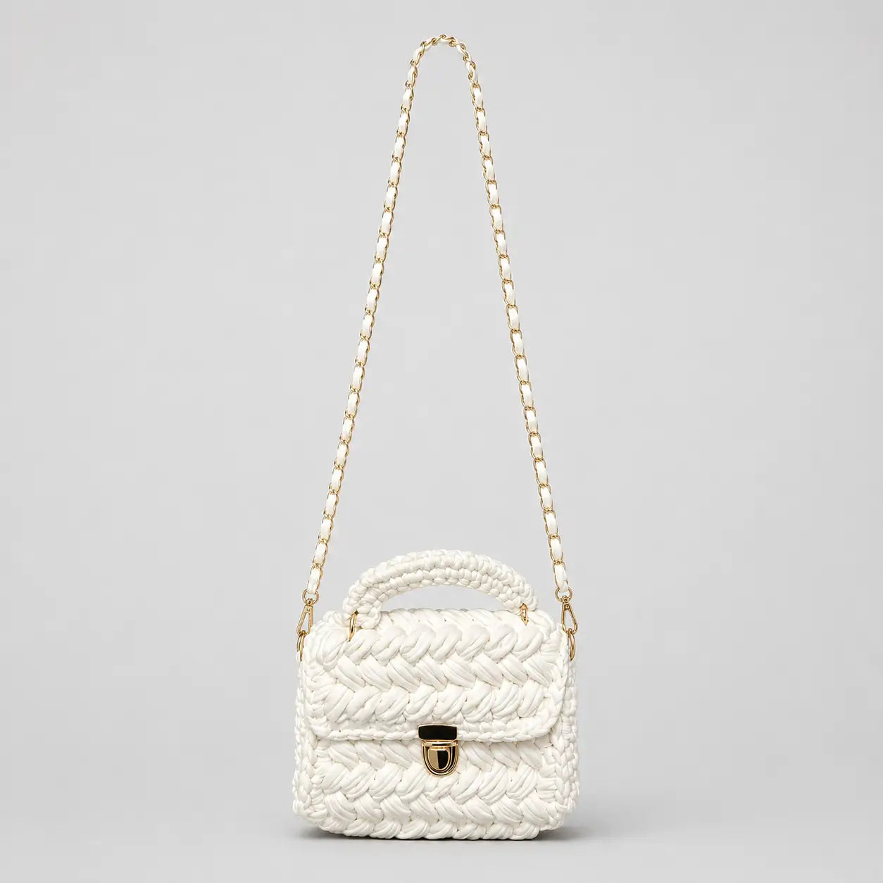 White chunky crochet top handle bag shown on a clean background with gold hardware and a detachable woven shoulder strap