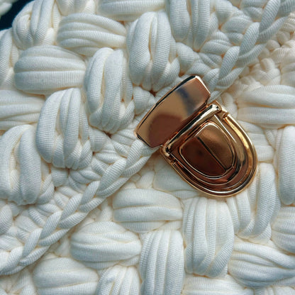 Close-up of the white chunky crochet bag showing the woven texture and polished gold push-lock clasp