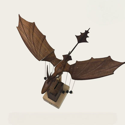 Front view of a wooden dragon automaton with articulated wings displayed on its mechanical base.