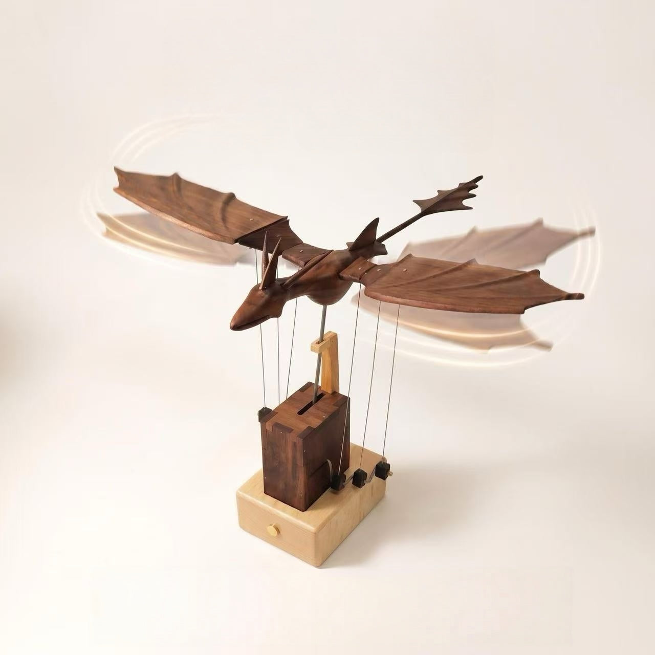 Side view of the handcrafted wooden dragon automaton with outstretched wings and a mechanical display base.