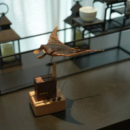 Side view of a wooden manta ray automaton showing the suspended sculpture and wooden mechanical base.
