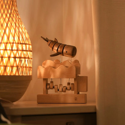Wooden kinetic whale decor displayed beside a warm table lamp